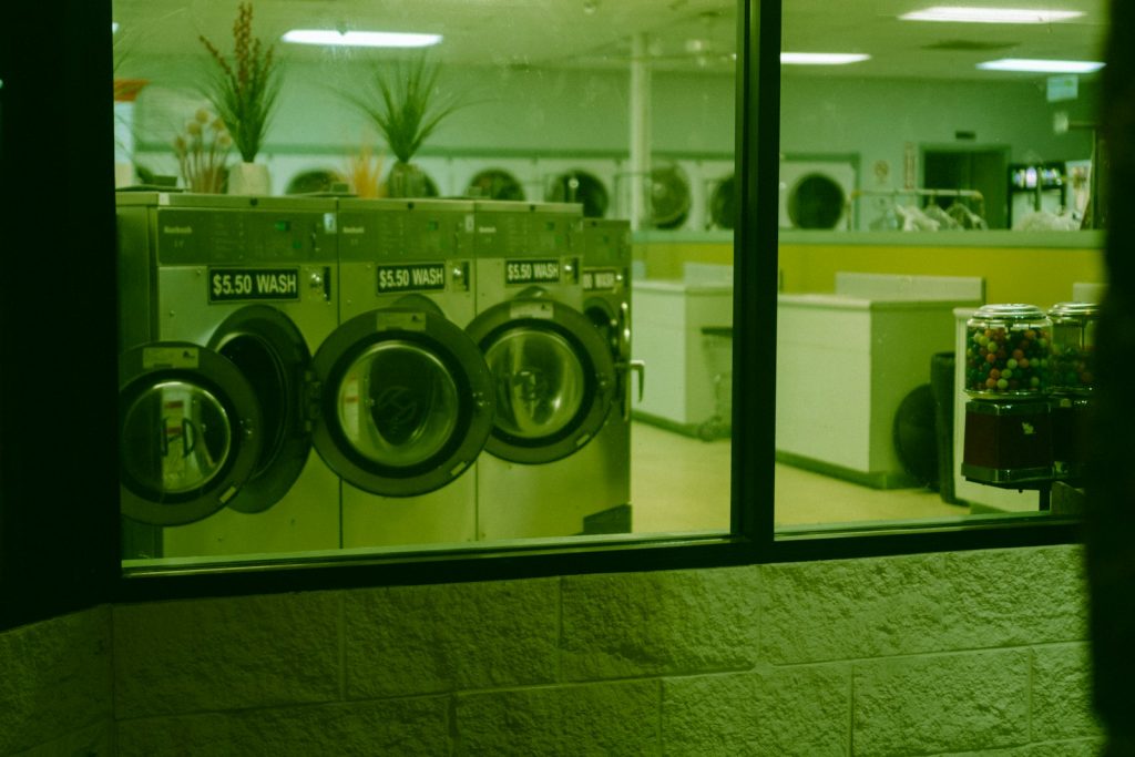 Mesin cuci front load putih berjajar di gerai laundry koin